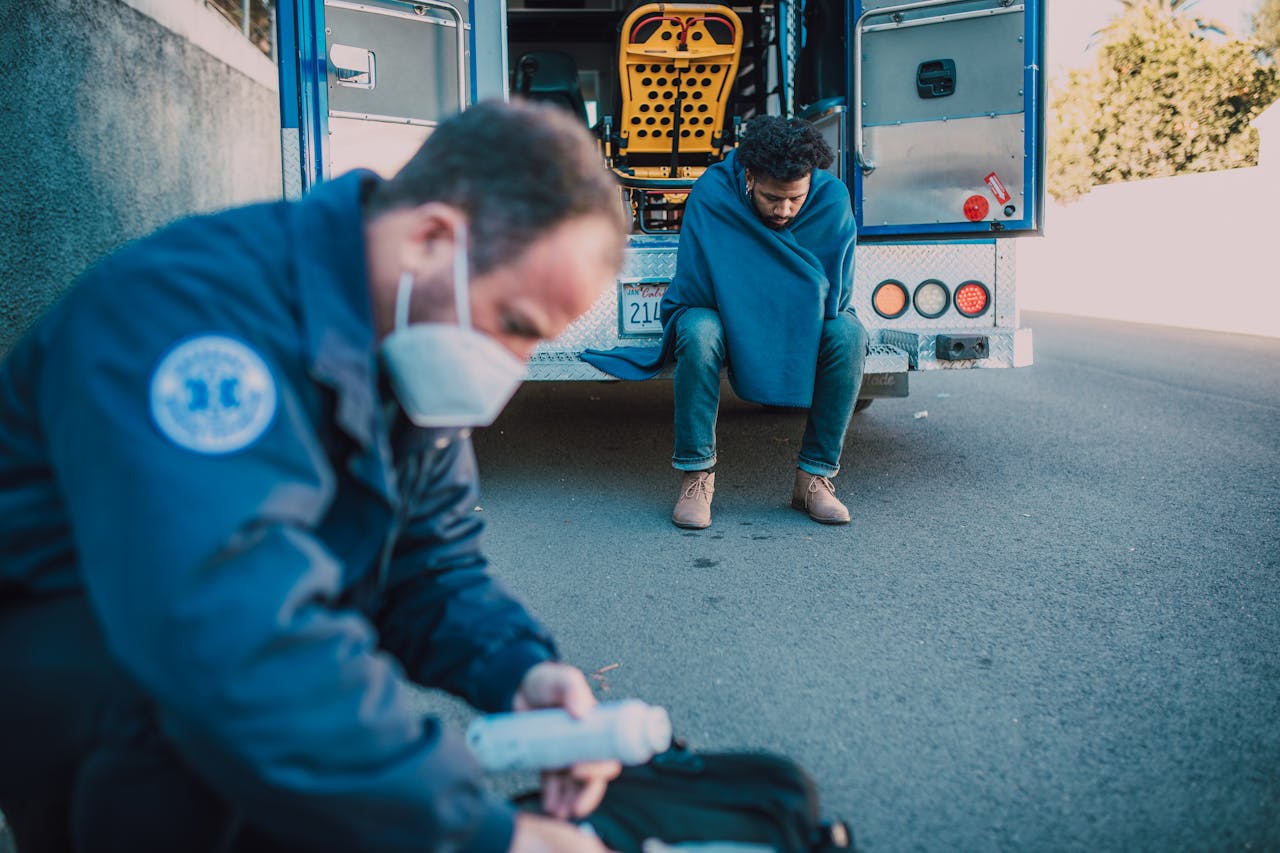 A paramedic attends to a patient outside an ambulance on a roadside, showcasing emergency care.
